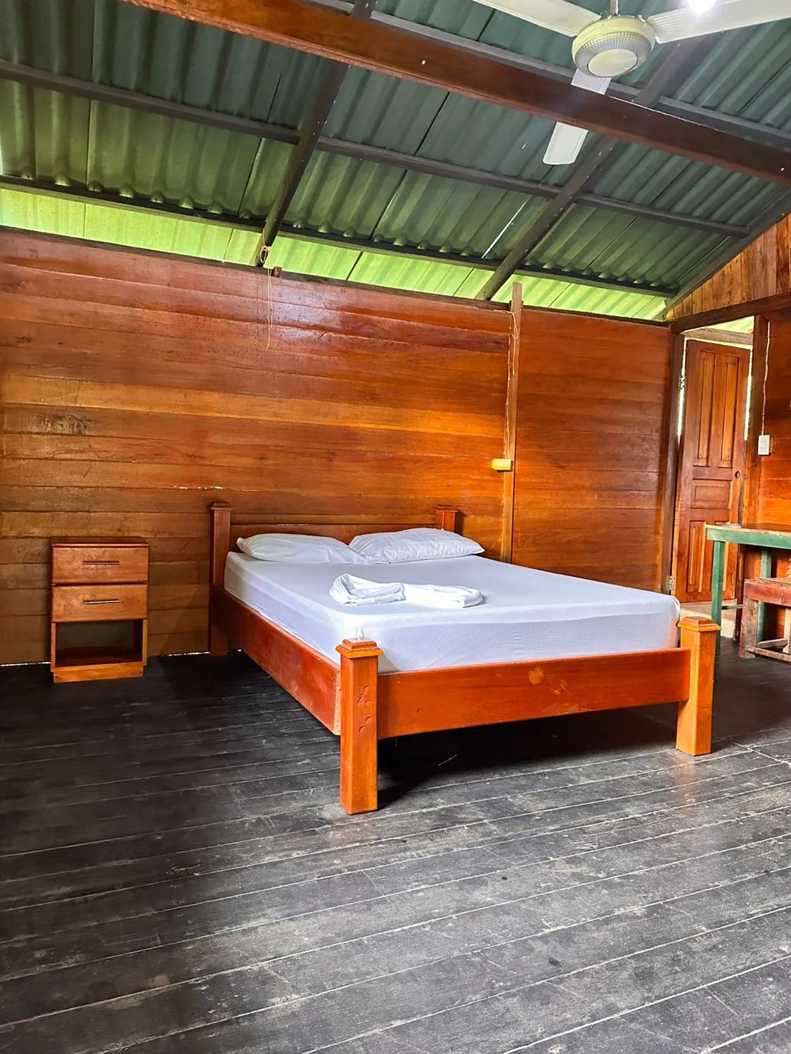 Habitación de madera con cama doble y mesa de noche
